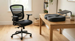Black mesh office chair beside a dark gray contoured seat cushion on a wooden desk