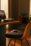 Laptop on a wooden desk with a chair in a softly lit room
